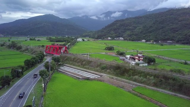 Aerial flight above the red Iron bridge, railway and rice fields  in Yuli, a township in the eastern rift valley, Hualien County, Taiwan.  - crane up