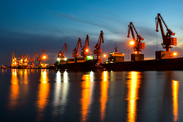 Fototapeta premium Night, cranes at harbour docks are busy working