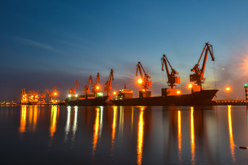 Fototapeta na wymiar Night, cranes at harbour docks are busy working