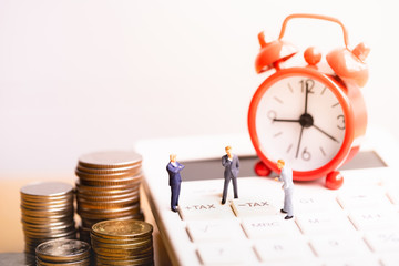 Businessmans and red alarm clock on calculator With the word Tax. Register of taxpayers for...