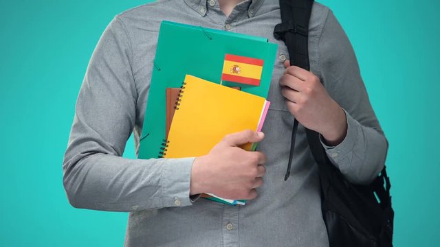 Student holding notebooks with Spanish flag, international education program