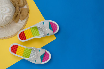 Hat and colorful shoes for women on blue and yellow background. The concept of a holiday by the sea. Flat lay.