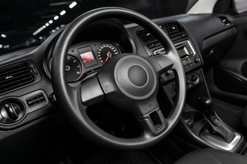 Interior view of car with black salon. Modern luxury prestige car interior:, dashboard, speedometer, tachometer  with white backlight  steering wheel  with car controller system function.