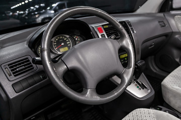 Close-up of the dashboard, speedometer, tachometer and steering wheel. Luxurious car interior details.