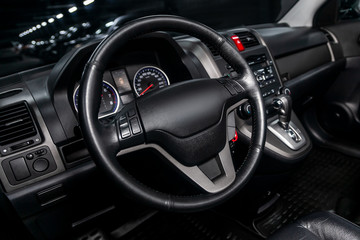 Fototapeta na wymiar Interior view of car with black salon. Modern luxury prestige car interior:, dashboard, speedometer, tachometer with white backlight steering wheel with car controller system function..