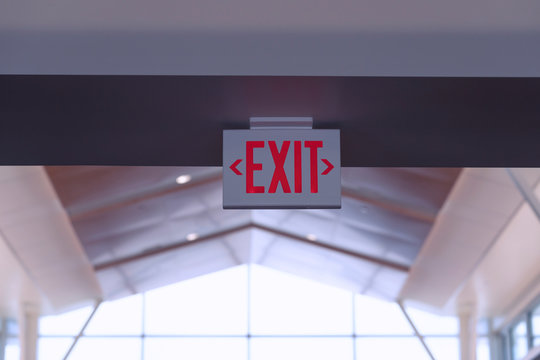 Exit Sign. Red Fire Escape Sign Hang on the Ceiling in the Airport. 