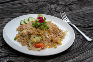 Fried rice with shrimps and vegetables in a white dish on an old wooden table, close up . Thai food , Thai cuisine