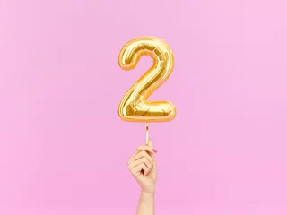 Fotobehang Two year birthday. Female hand holding Number 2 foil balloon. Two-year anniversary background. 3d rendering © vpanteon