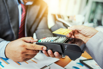 Fototapeta premium Hand of business man customer paying with NFC technology contactless credit card.