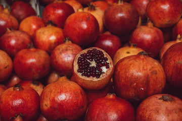 Pomegranates fruits in market. Background texture. One half opened pomegranate and many others closed.