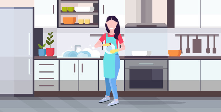 woman washing dishes housewife wiping plates with towel dishwashing concept girl in apron doing housework modern kitchen interior horizontal flat full length
