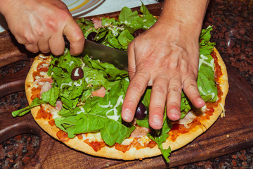 Tasty appetizing pizza with cheese, tomatoes, arugula, olives, basil on wooden table