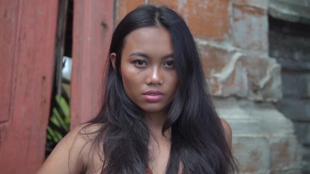 close-up beautiful asian woman with long black hair posing against brick wall