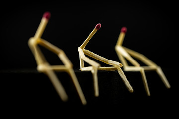 image of three men with matchsticks sitting in the dark, one of them sad and erased. Concept of...