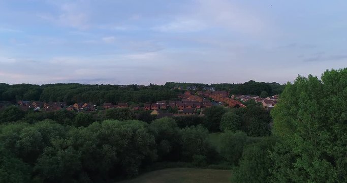 Aerial drone shot of little town next to Leeds in the United Kingdom - Shot over green fields with view of town - 4K at 60fps