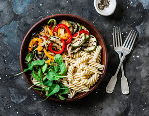 Roasted vegetables and fusilli pasta antipasti salad on dark background, top view