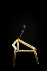 image of a man made of matchstick. Small and depressive in the dark, erased and losing the flame....