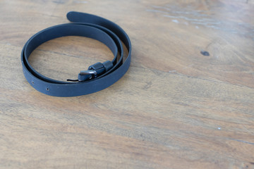 black leather belt on wooden table.