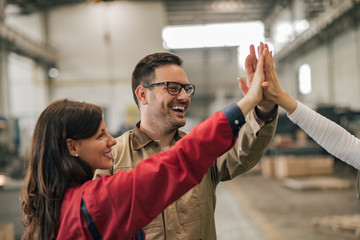 Positive factory workers group giving high five.