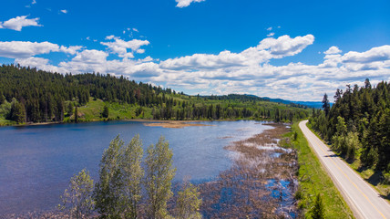 Aerial of road alongside lake on a beautiful summer day