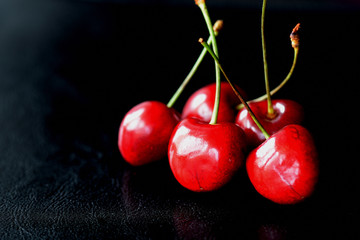 Five ripe berries of a sweet cherry on a dark background close up