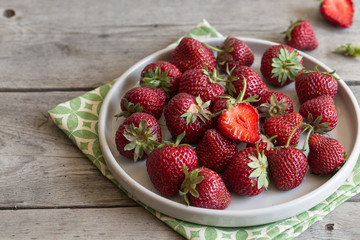 ripe juicy strawberries in a clay plate on a light background with copy space/