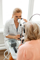 Attentive doctor with tied blonde hair looking in binoculars