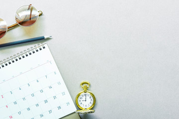 Work schedule and planning concept. Calendar, pencil, golden pocket watch and sunglasses on desk with free space.