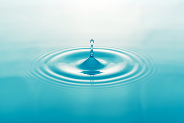 One blue drop of water on surface of water background