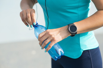 Importance of hydration during exercise concept, with young woman drinking water after workout