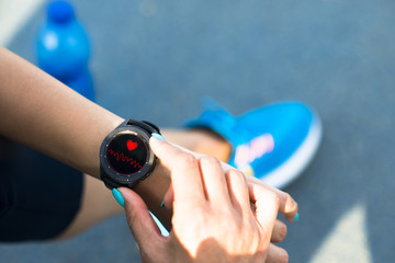 Athlete in sportswear verifying heart rate on modern smart watch after training  