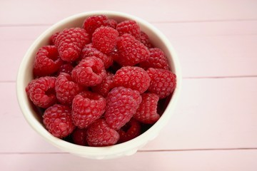raspberry berry close-up.  red raspberry in a pink round cup on pastel pink wooden background.Summer berry.