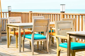 Woods tables and chairs in lounge beside sea view.