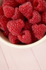 raspberry berry close-up. ripe red raspberry in a  cup on pastel pink wooden background.Summer berry.