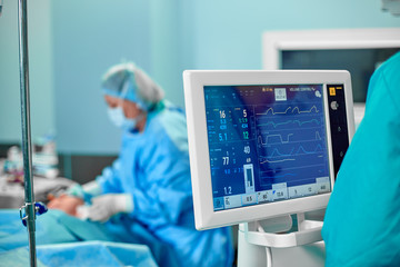 Electrocardiogram in hospital surgery operating emergency room showing patient heart rate with blur...