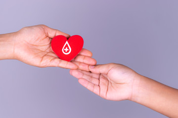 Woman hand gives a red heart to a boy hand for blood donation concept,World blood donor day. Copy...