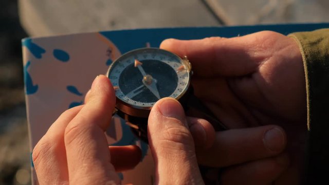 Close up on compass instrument in gloved hand . Mountain hiking trails. Fores trip concept.