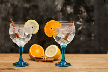 two gin tonics with orange, lemon and cinnamon