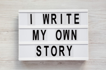 'I write my own story' words on a modern board on a white wooden background, top view. From above, overhead, flat lay. Close-up.