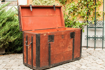 Old vintage retro wooden chest with iron strapping on stone paved house backyard