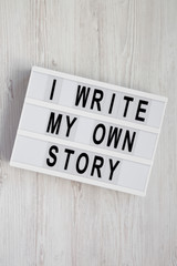 'I write my own story' words on a modern board on a white wooden surface. From above, overhead, flat lay, top view.