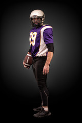 Fototapeta na wymiar American football player posing with ball on black background