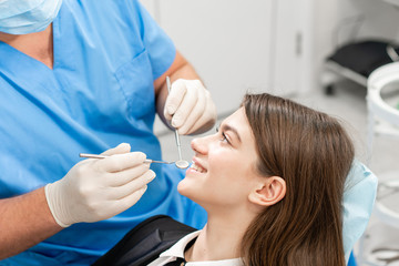 Naklejka premium Young beautiful woman in the dentist chair at dental clinic. Medicine, health, stomatology concept. dentist treating a patient. Woman smiling
