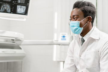 Young African male dentist shows x-rays on the monitor. Medicine, health, stomatology concept. dentist treating a patient.