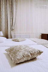 Pillows on the bed in the interior of an economy class hotel room in natural evening electric lighting
