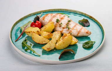 Grilled chicken fillet with fried potatoes. On light background