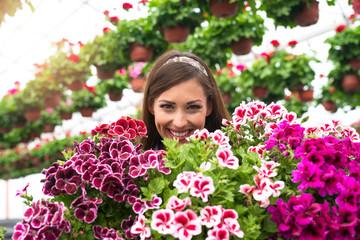 Close up view of beautiful adorable caucasian woman florist face surrounded by flowers in greenhouse garden.