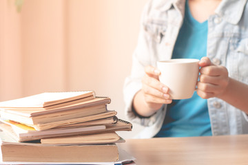 Stack of book on table with Woman drinking coffee.