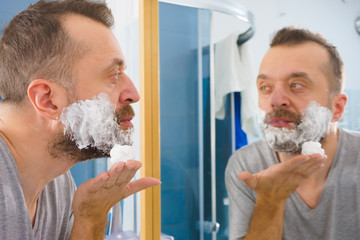 Guy shaving his beard in bathroom