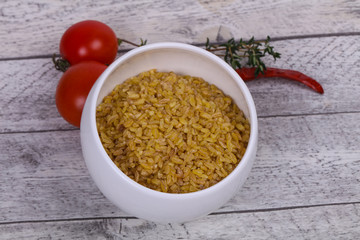 Raw bulgur in the bowl with tomatoes and garlic